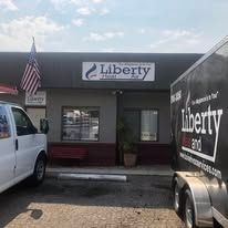 A white van and a black trailer are parked in front of a building.