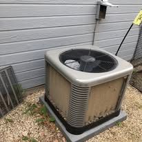 A dirty air conditioner is sitting outside of a house.