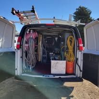 The back of a van filled with tools and a ladder.