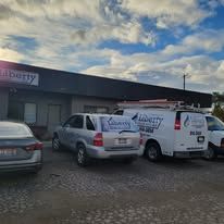 A couple of cars and a van parked in front of a building.