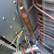 A close up of a refrigerator with a lot of wires coming out of it.