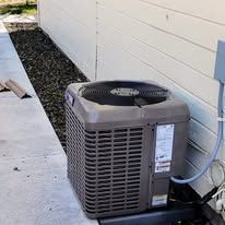 An air conditioner is sitting on the side of a house.