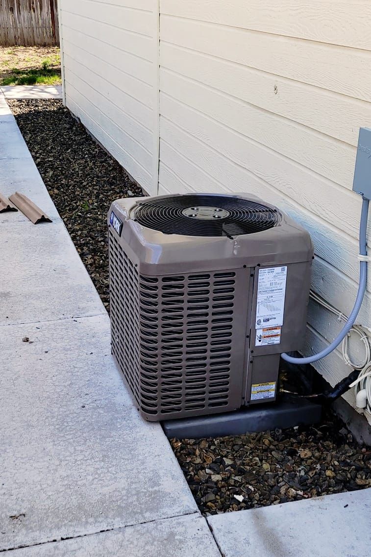 An air conditioner is sitting on the sidewalk next to a wall.