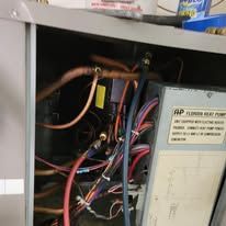 The inside of a refrigerator with a lot of wires coming out of it.