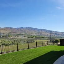 A backyard with a fence and mountains in the background.