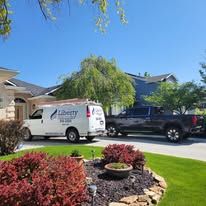 A white van and a black truck are parked in front of a house.