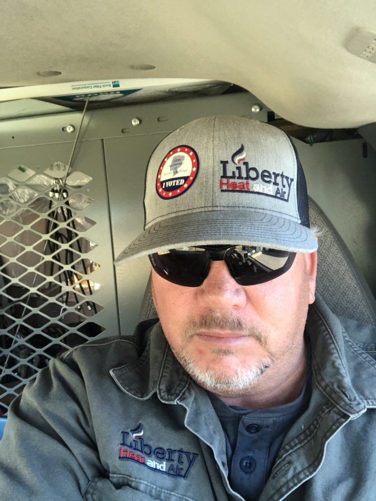 A man wearing a hat and sunglasses is sitting in a van.