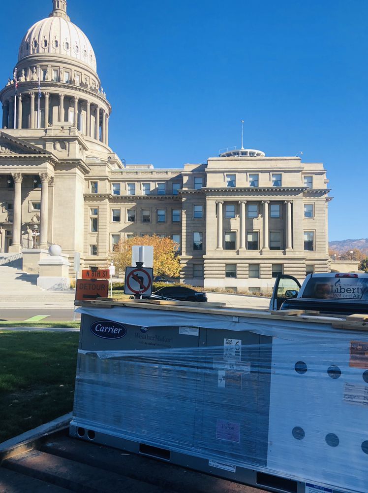 A truck is carrying a stack of boxes in front of the capitol building.