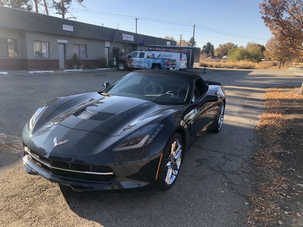 A black sports car is parked in a parking lot in front of a building.