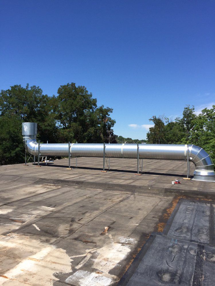 A long metal pipe is sitting on top of a roof.