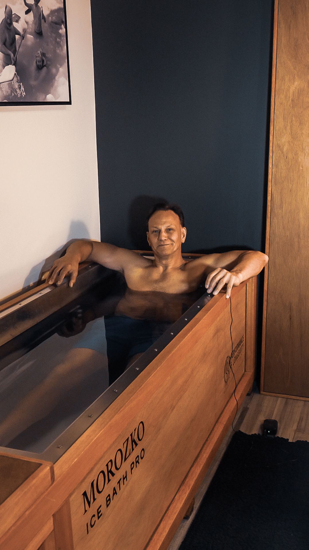 A man and a woman are sitting in a wooden bathtub.