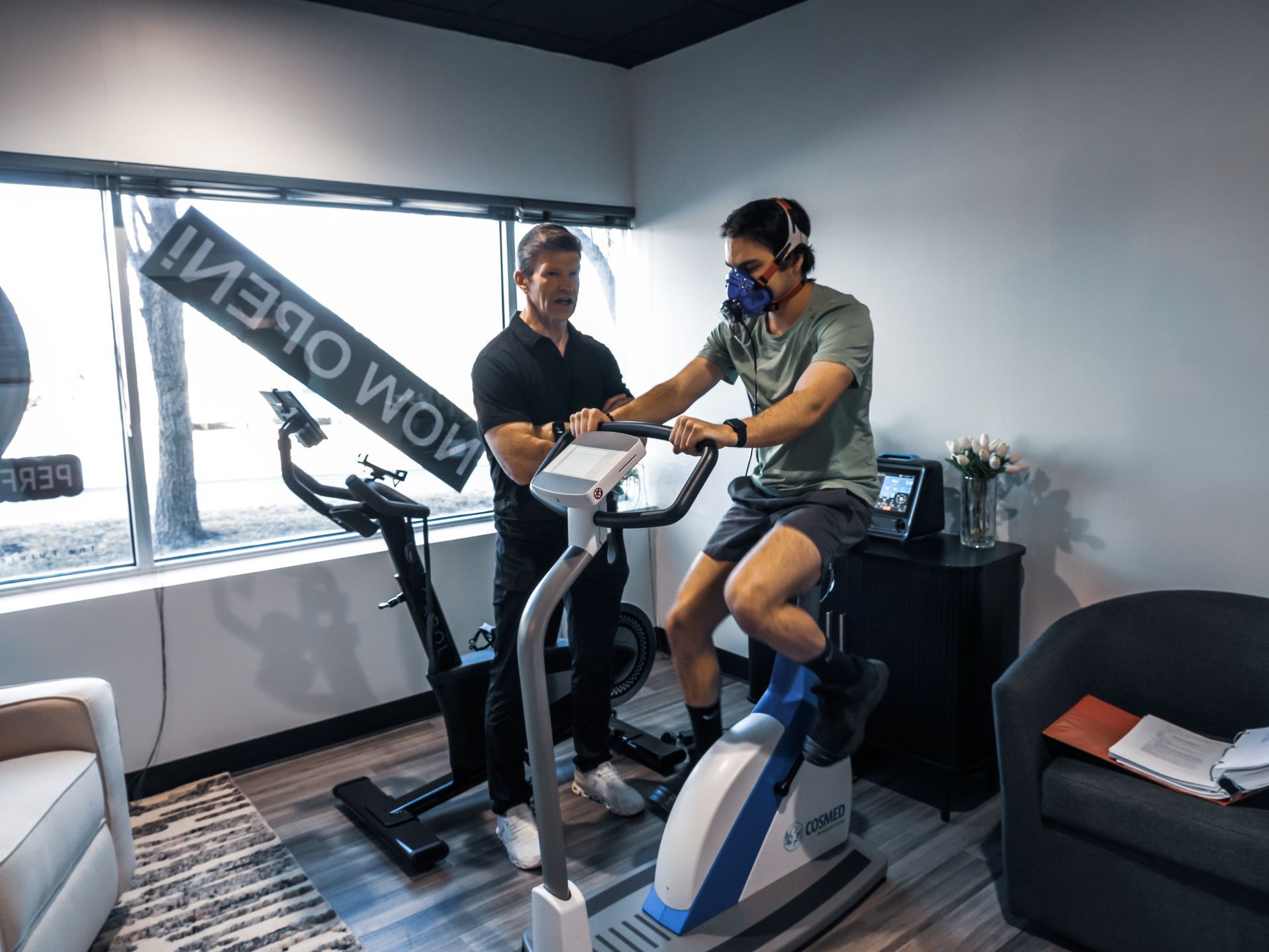 A woman wearing a mask is riding an exercise bike