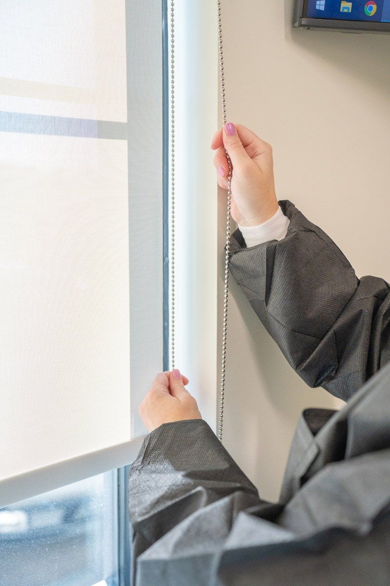 A person is adjusting a roller blind on a window.