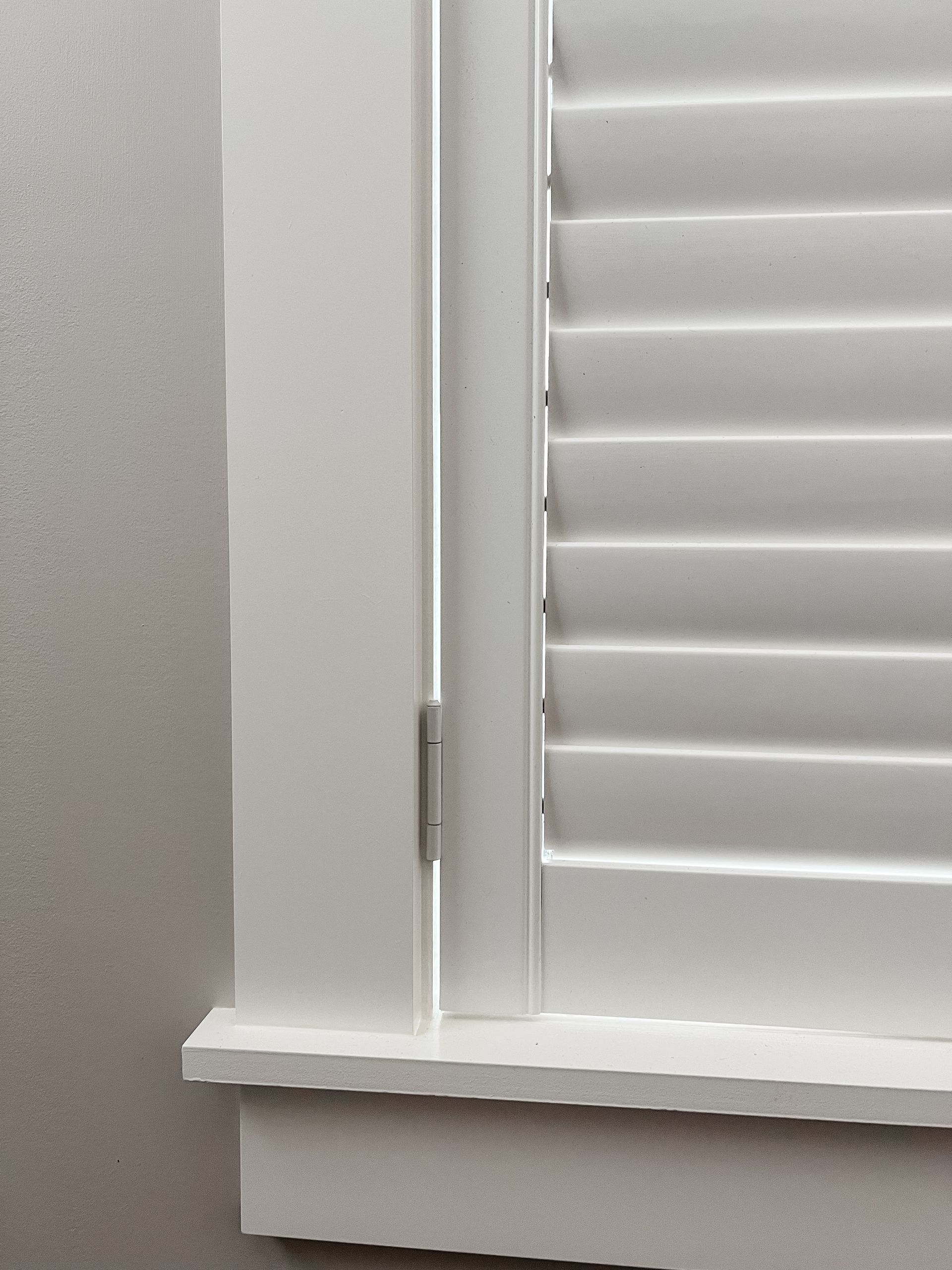 A close up of a window with white shutters on it.