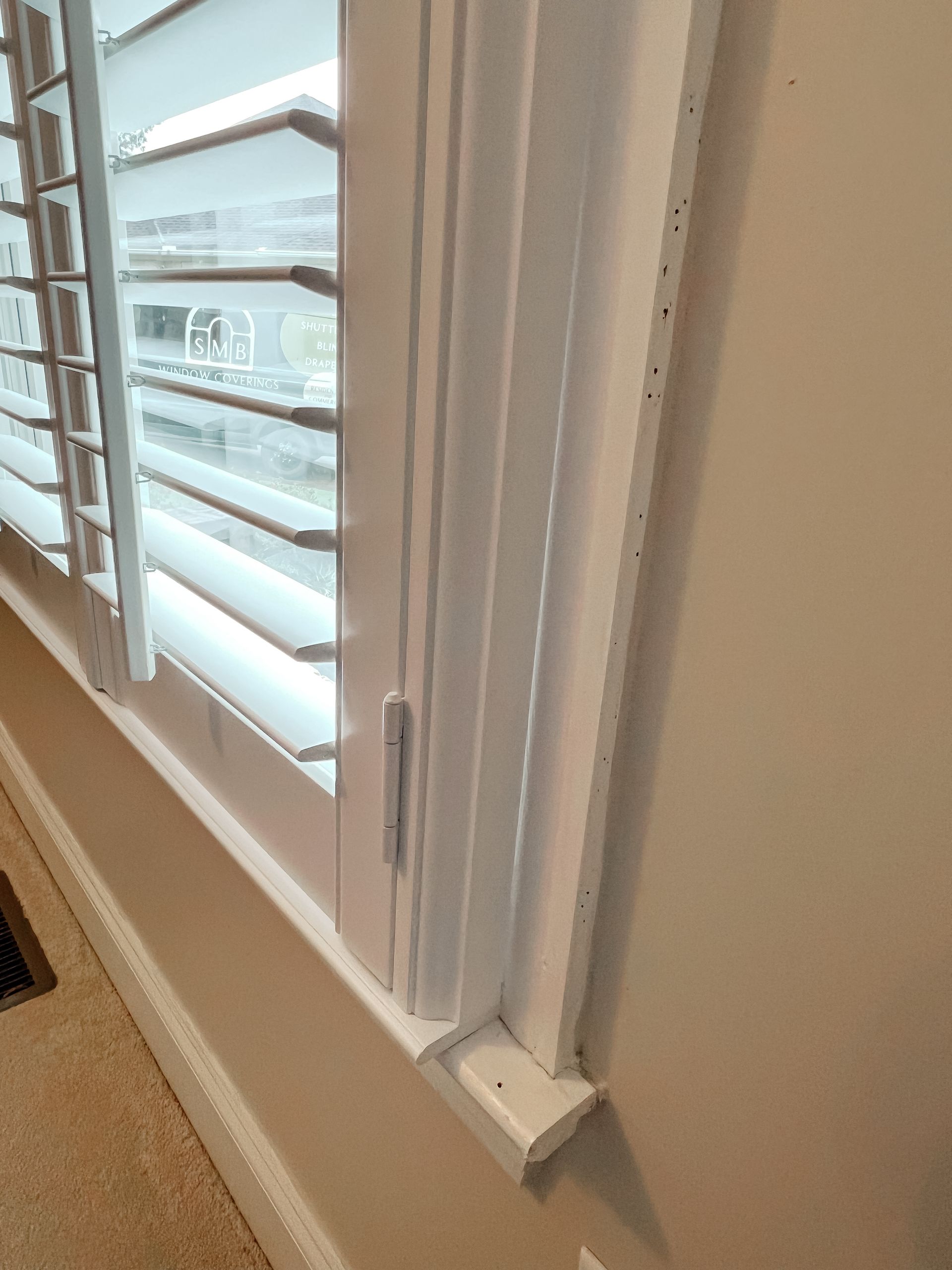 A close up of a window with white shutters in a room.