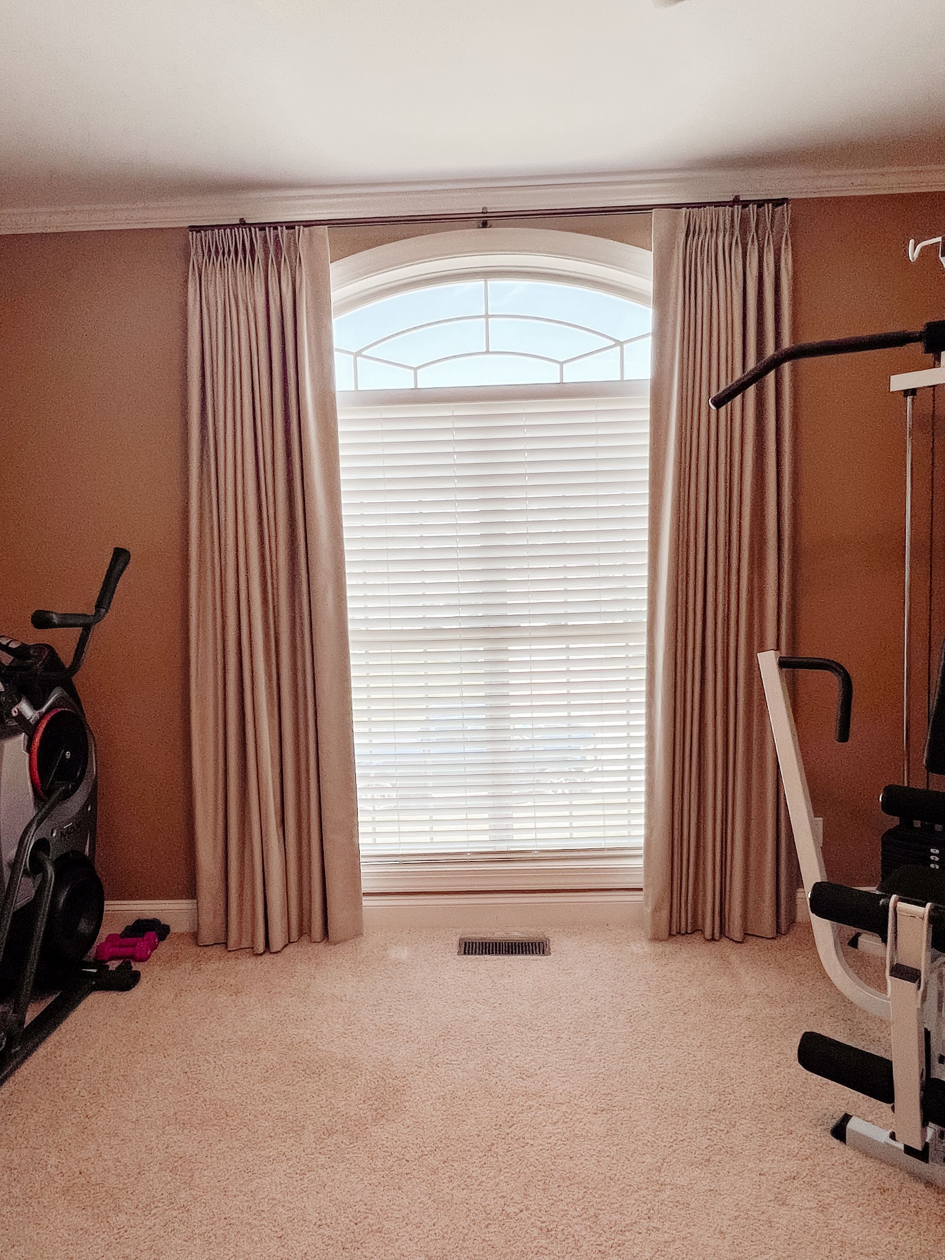 A room with a window with custom drapes and a bicycle in it