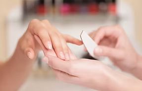 Close-up of hand with short nails painted in shades of pastel pink, lavender, and green.