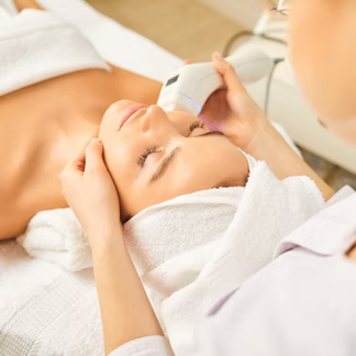 Woman receiving facial treatment in a spa, using a device on her face.