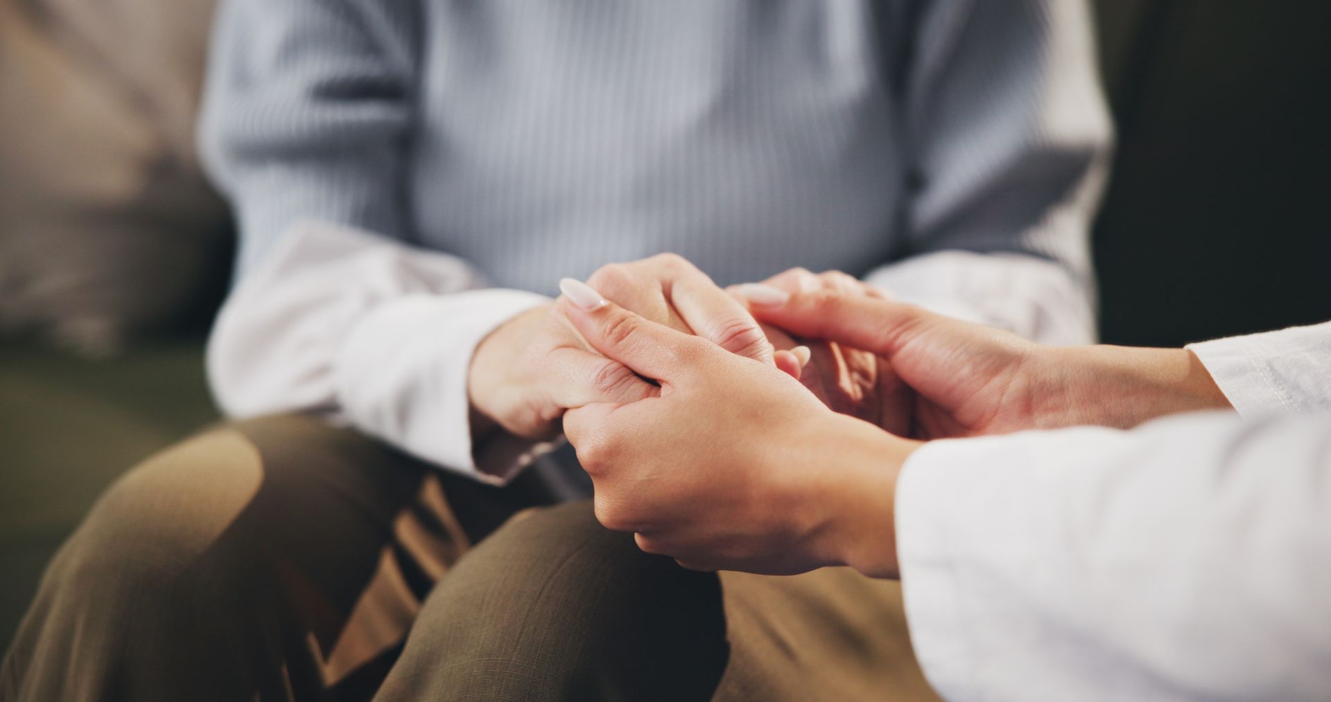 Hands of one person held by another in a supportive gesture.