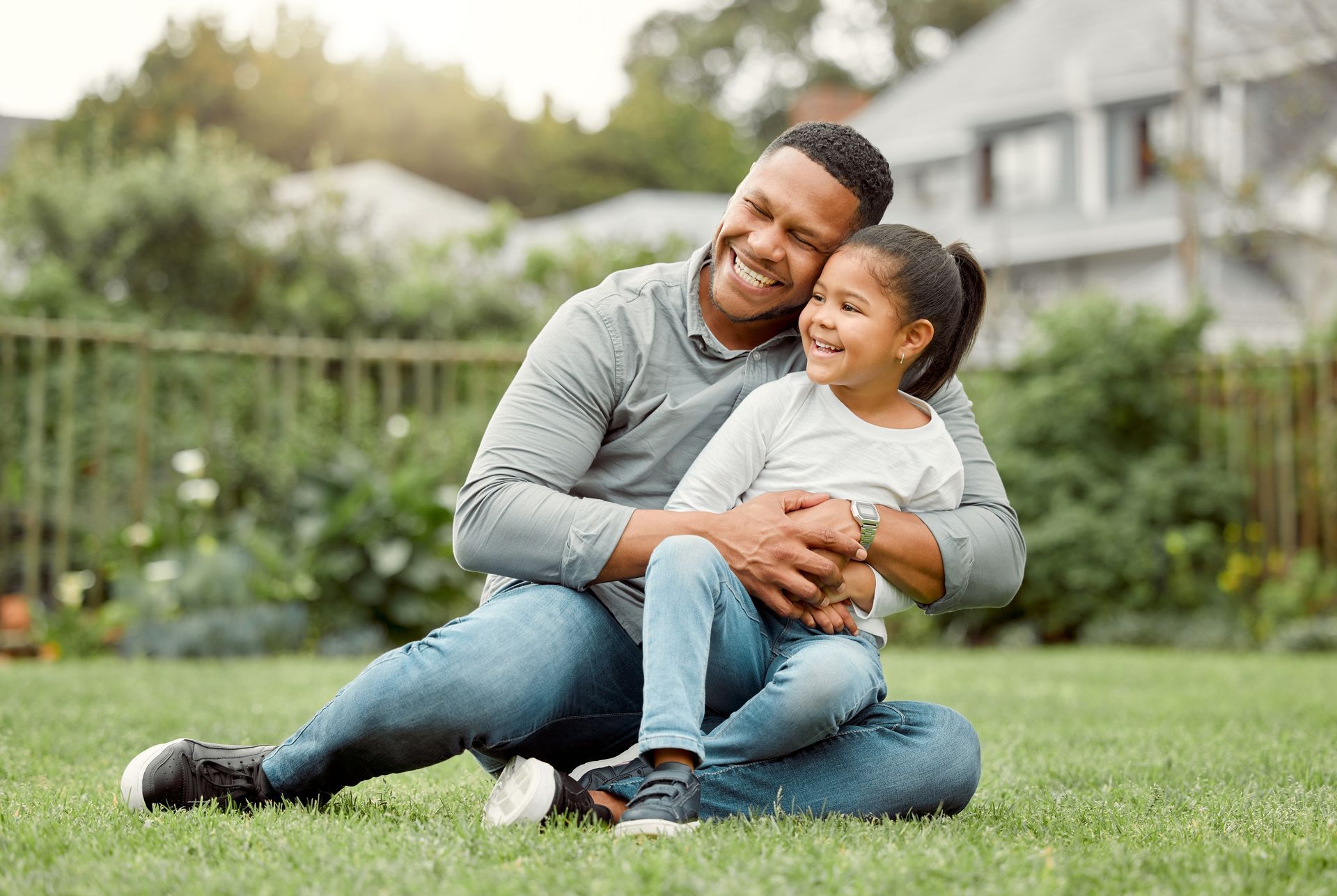 Man and girl sitting on grass and smiling. 
