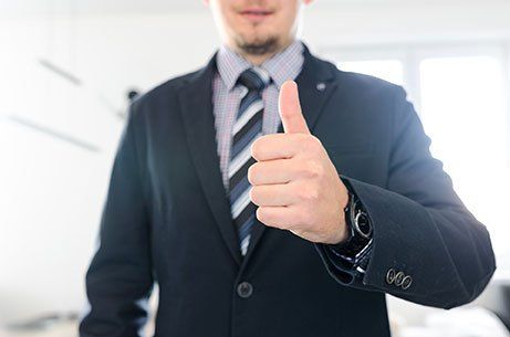 A man in a suit and tie is giving a thumbs up.