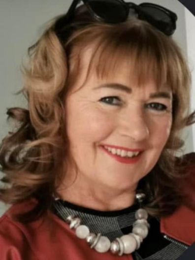 A woman wearing sunglasses and a pearl necklace smiles for the camera.