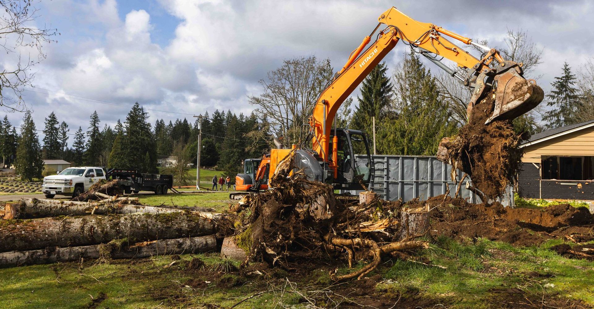 A large excavator is moving a large pile of dirt in a field.