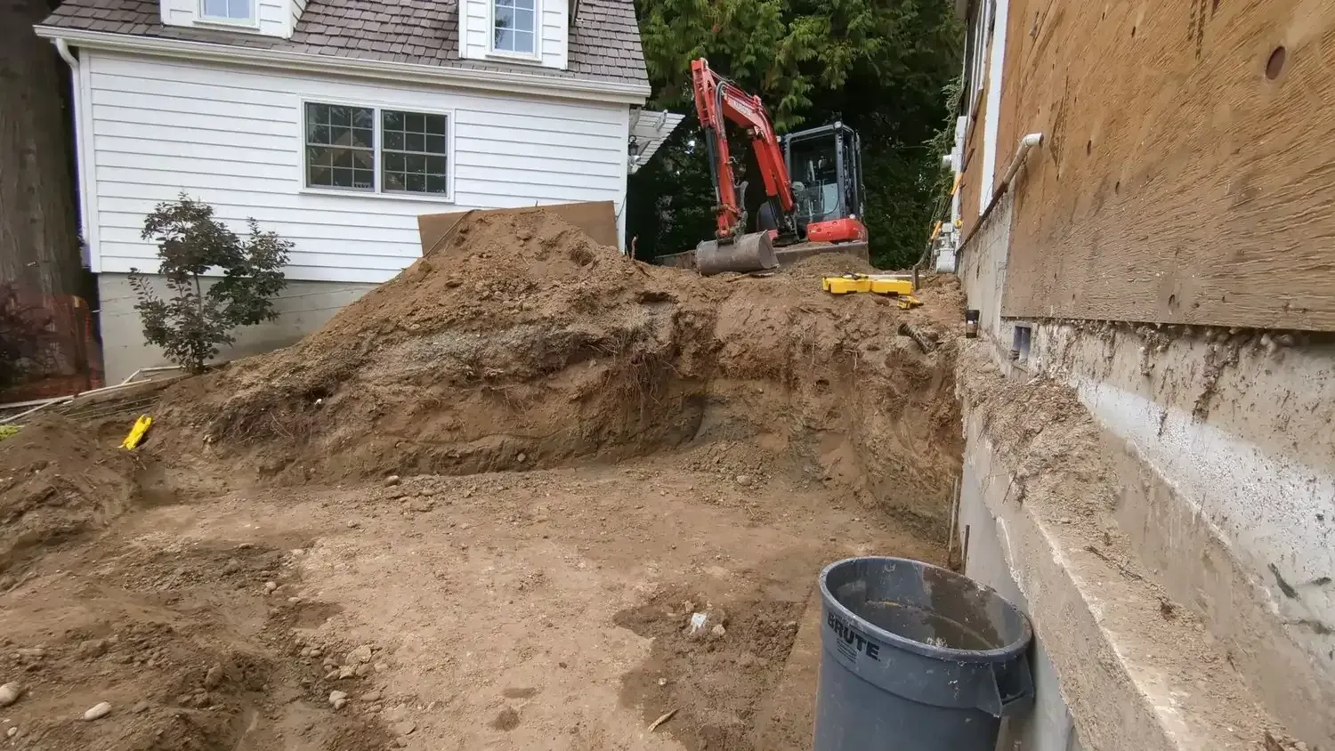 An excavator is digging a hole in front of a house