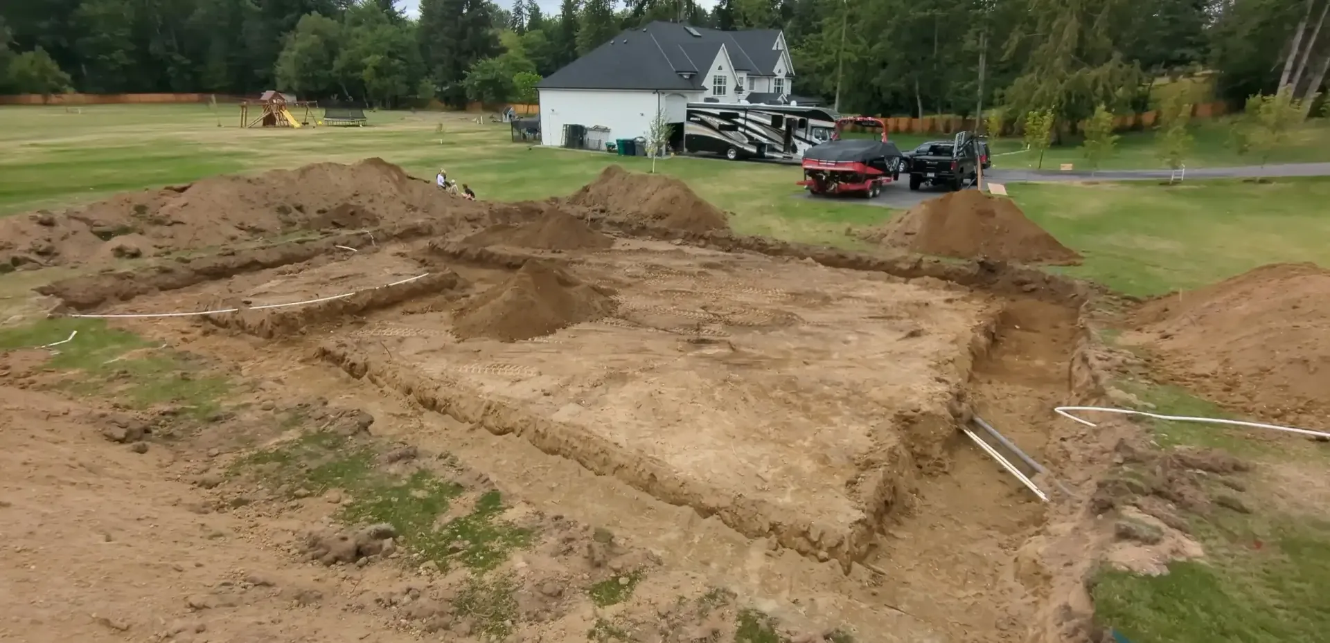 An aerial view of a dirt field with a house in the background.