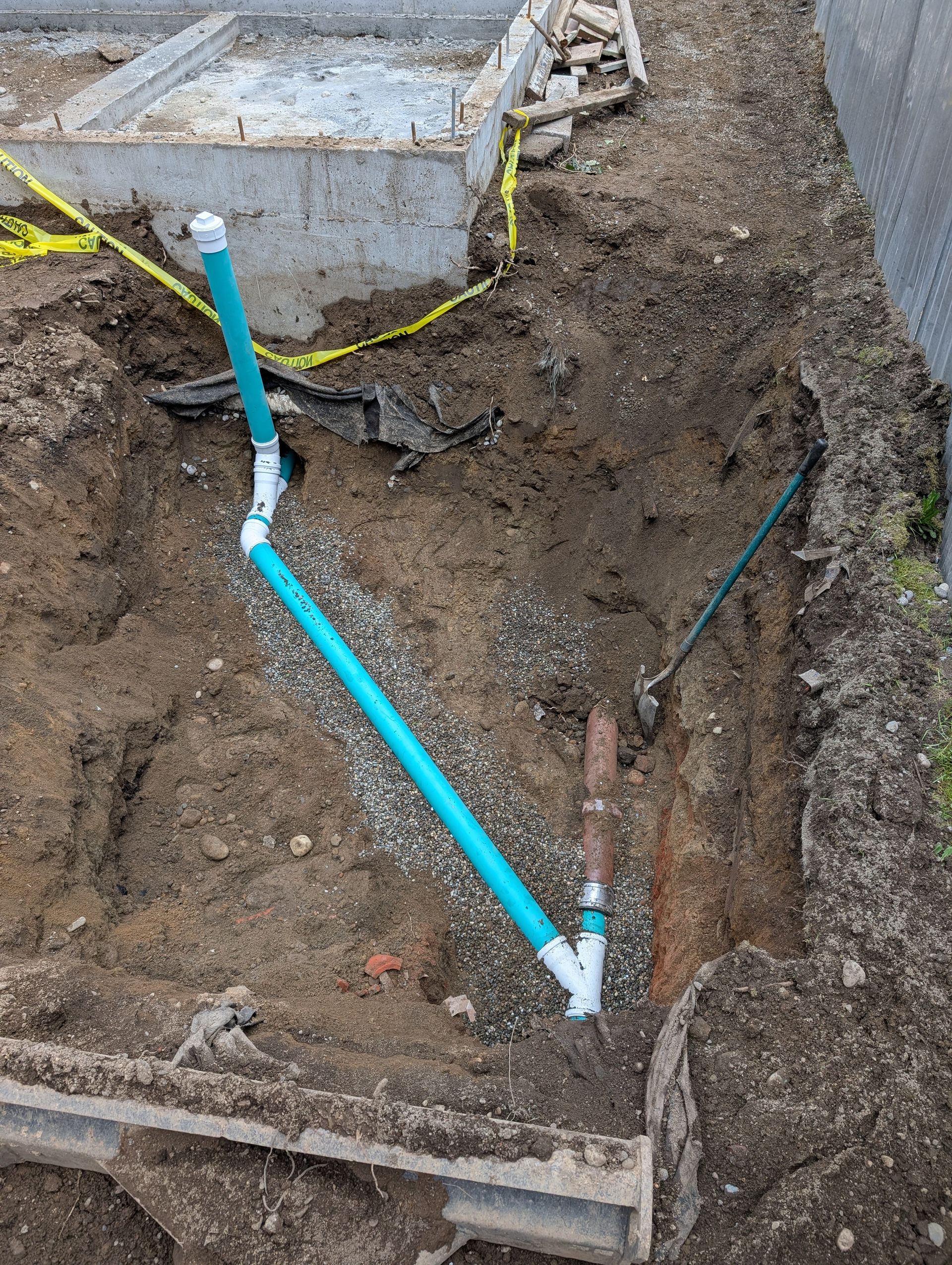 A blue pipe is laying in the dirt next to a shovel.