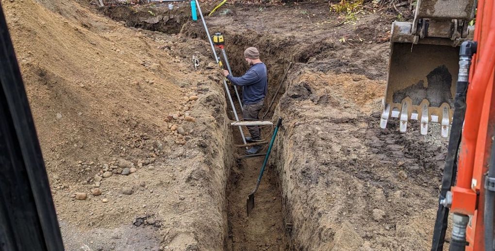 A man is standing on a ladder in a hole in the ground.
