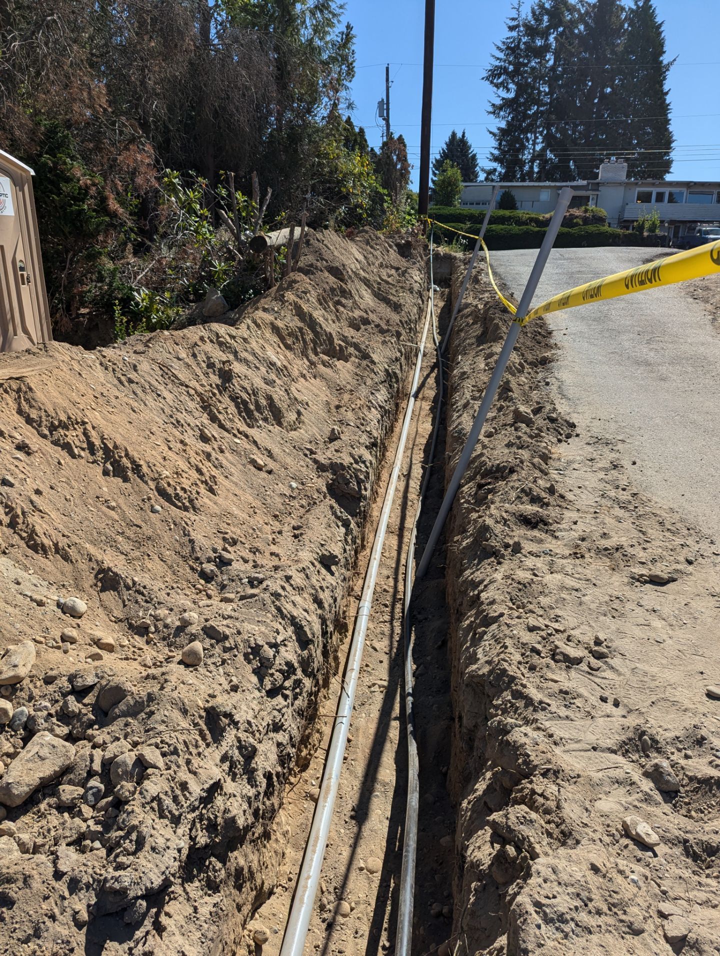 A pipe is being installed in the dirt next to a road.