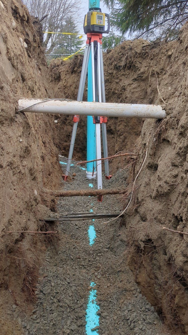 A pipe is being installed in a trench next to a tripod.