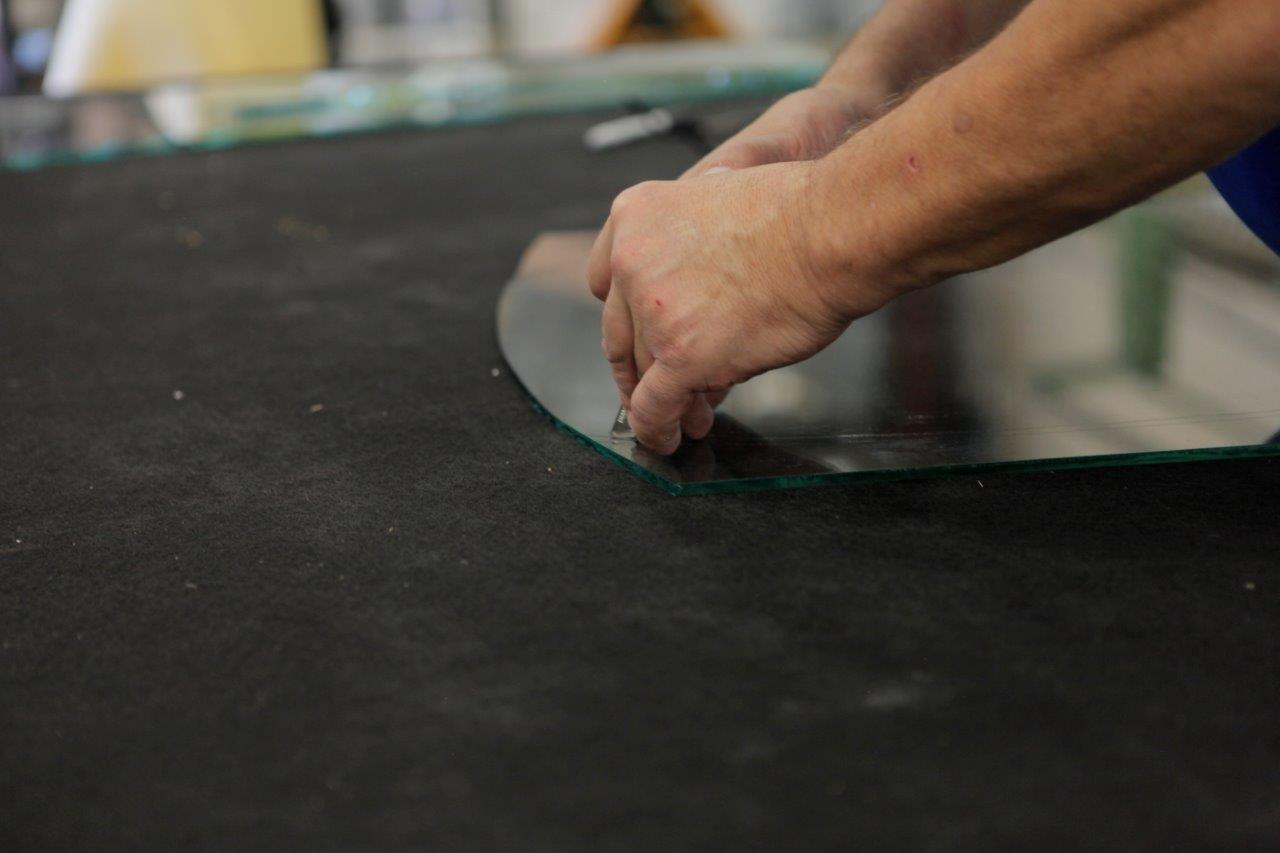 A person is cutting a piece of glass on a table.