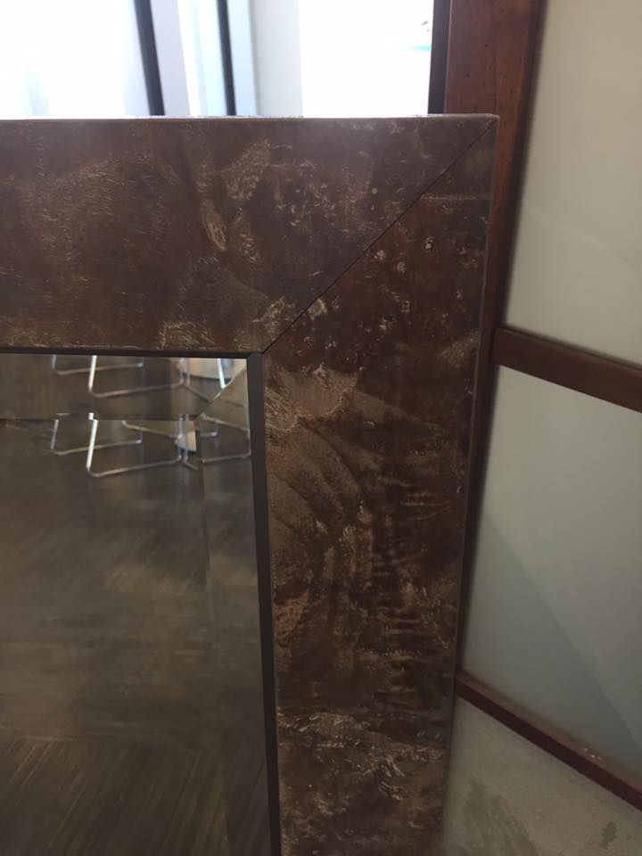 A mirror with a brown frame is sitting on a wooden floor.