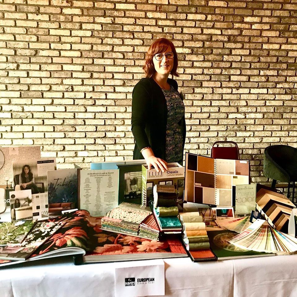 A woman is standing in front of a table with a brick wall in the background.
