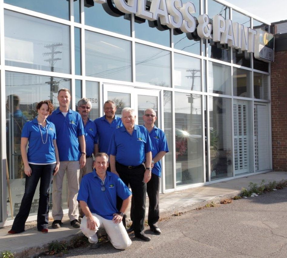 A group of people posing in front of a glass and paint store