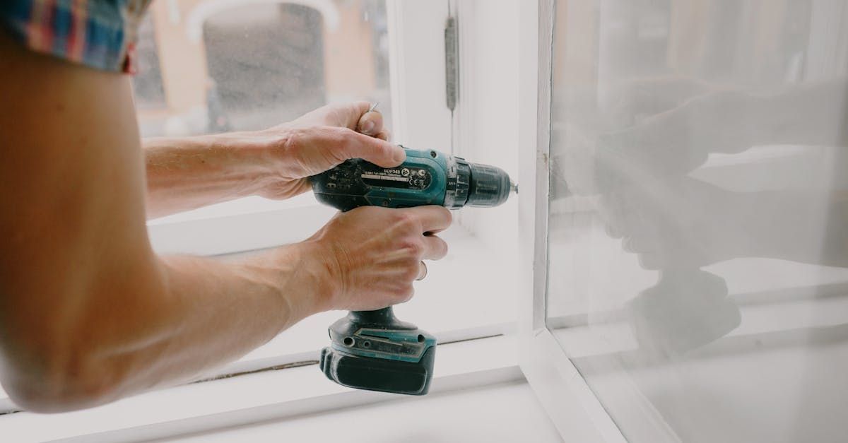 Person using a cordless drill on a white frame.