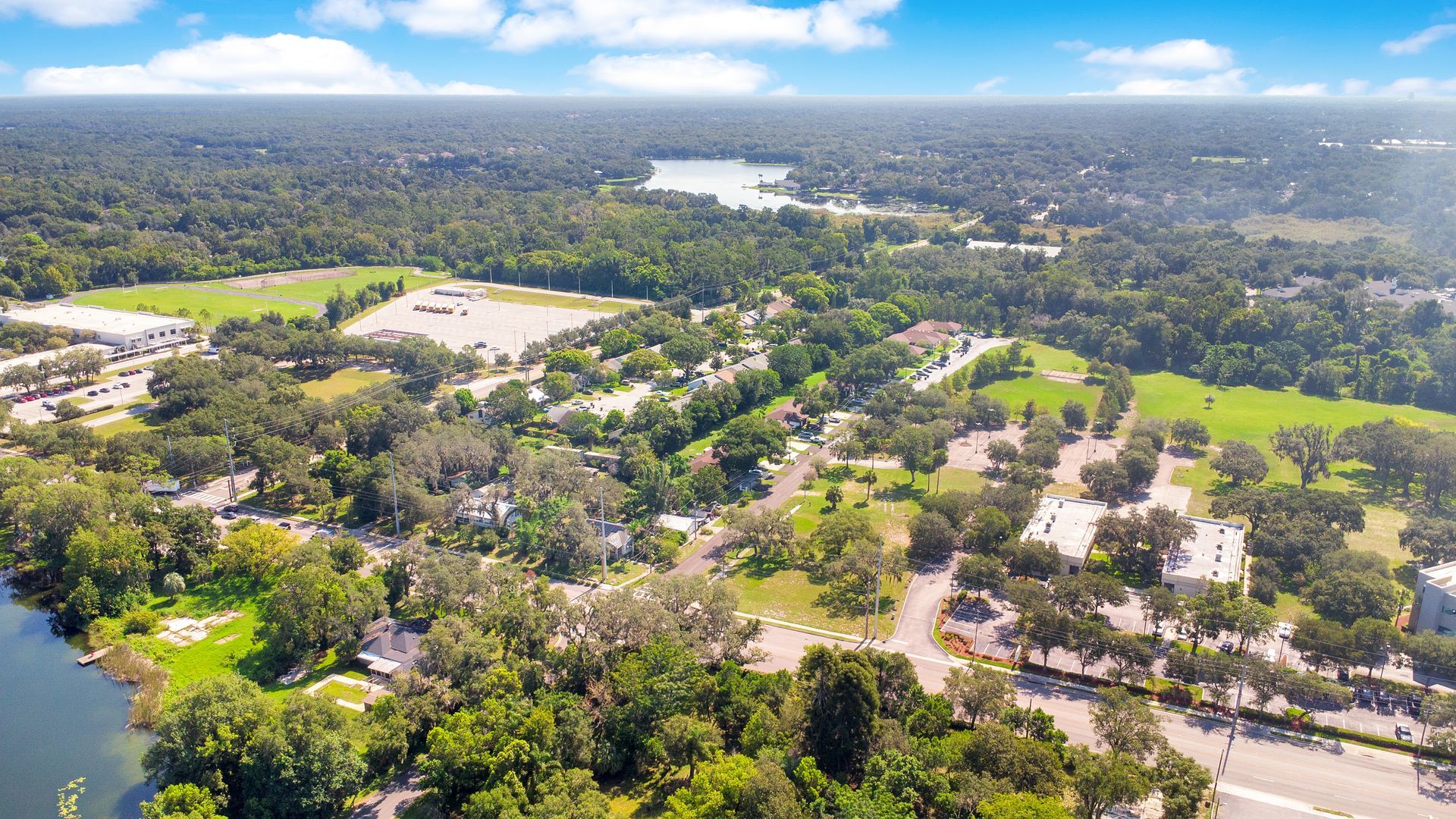 An aerial view of a residential area surrounded by trees and a lake.