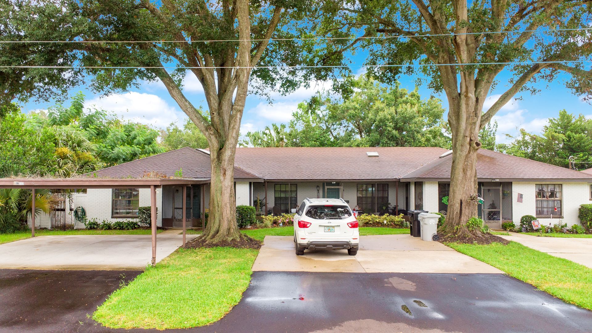 A white car is parked in front of a house.