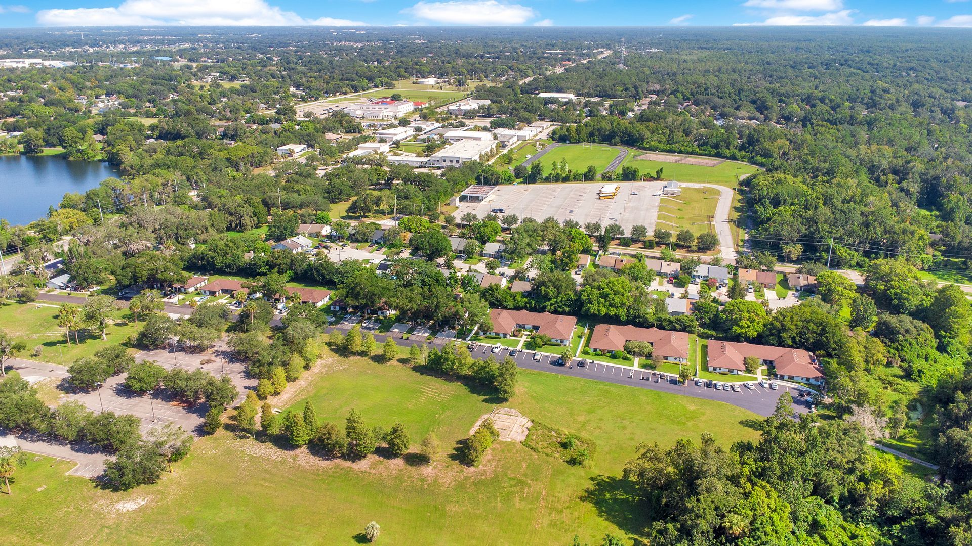An aerial view of a residential area surrounded by trees and a lake.