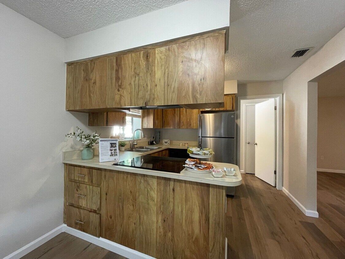 A kitchen with wooden cabinets and a stainless steel refrigerator.