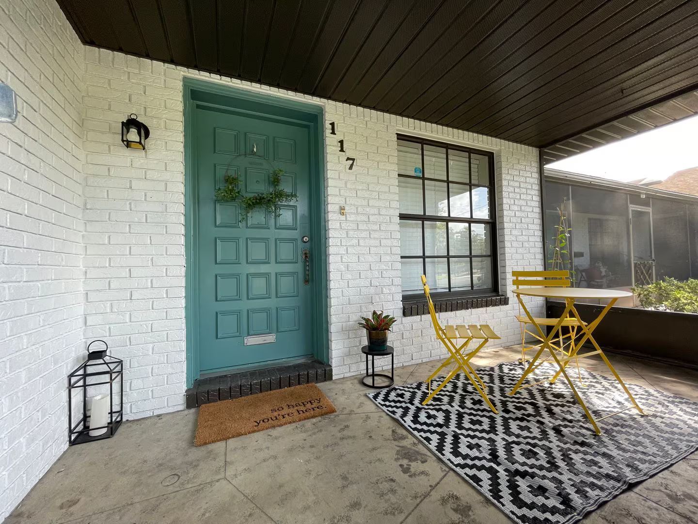 A porch with a table and chairs and a blue door.