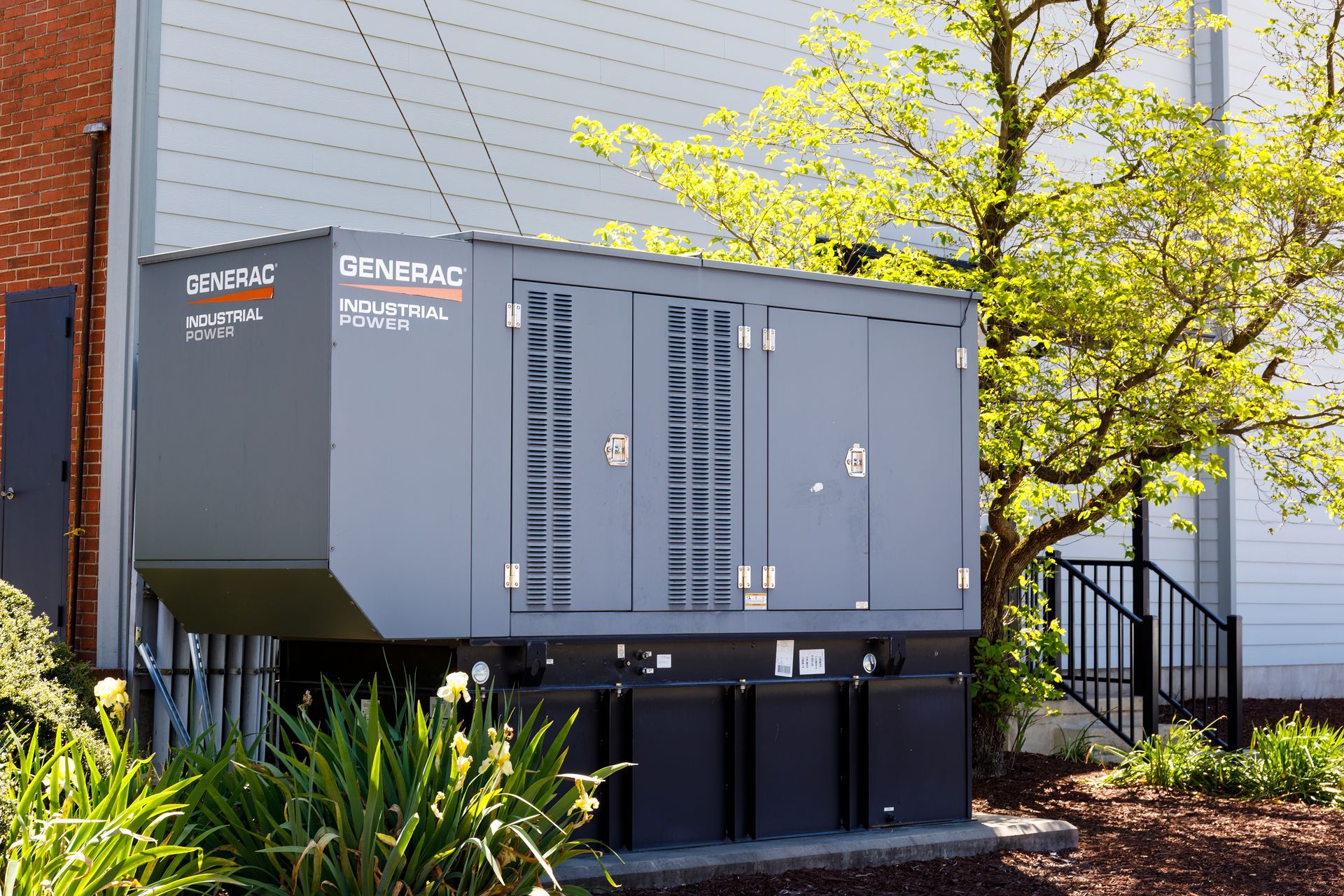 Générateur commercial gris à l'extérieur d'un bâtiment, avec panneaux de ventilation et le nom « Generac ».
