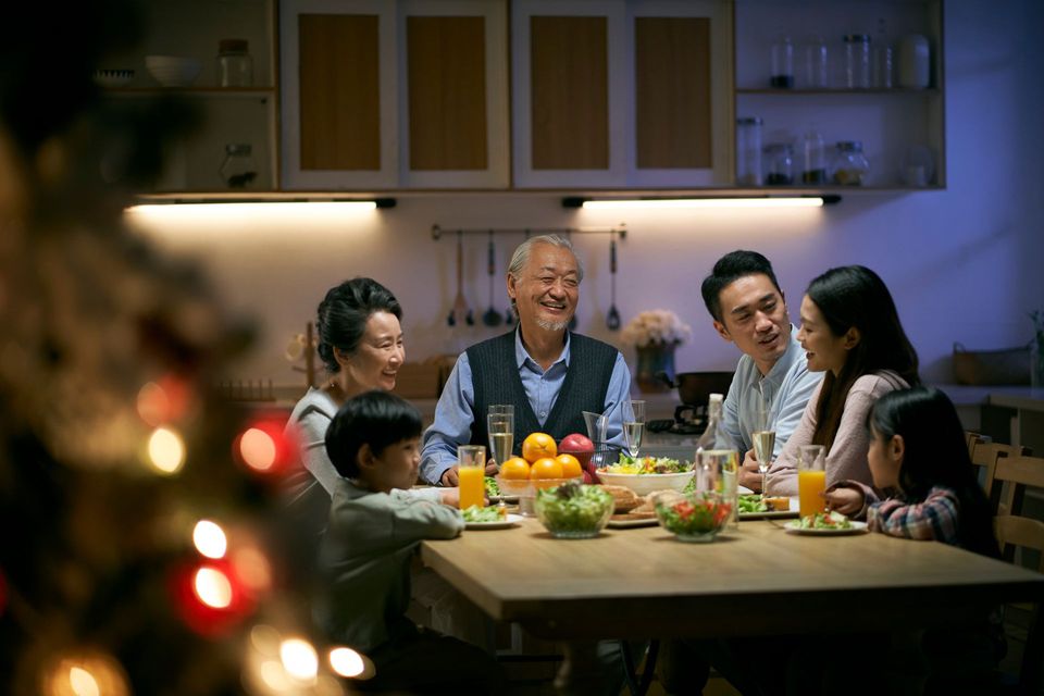 Famille réunie autour d'une table, souriante, dans une cuisine chaleureusement éclairée.