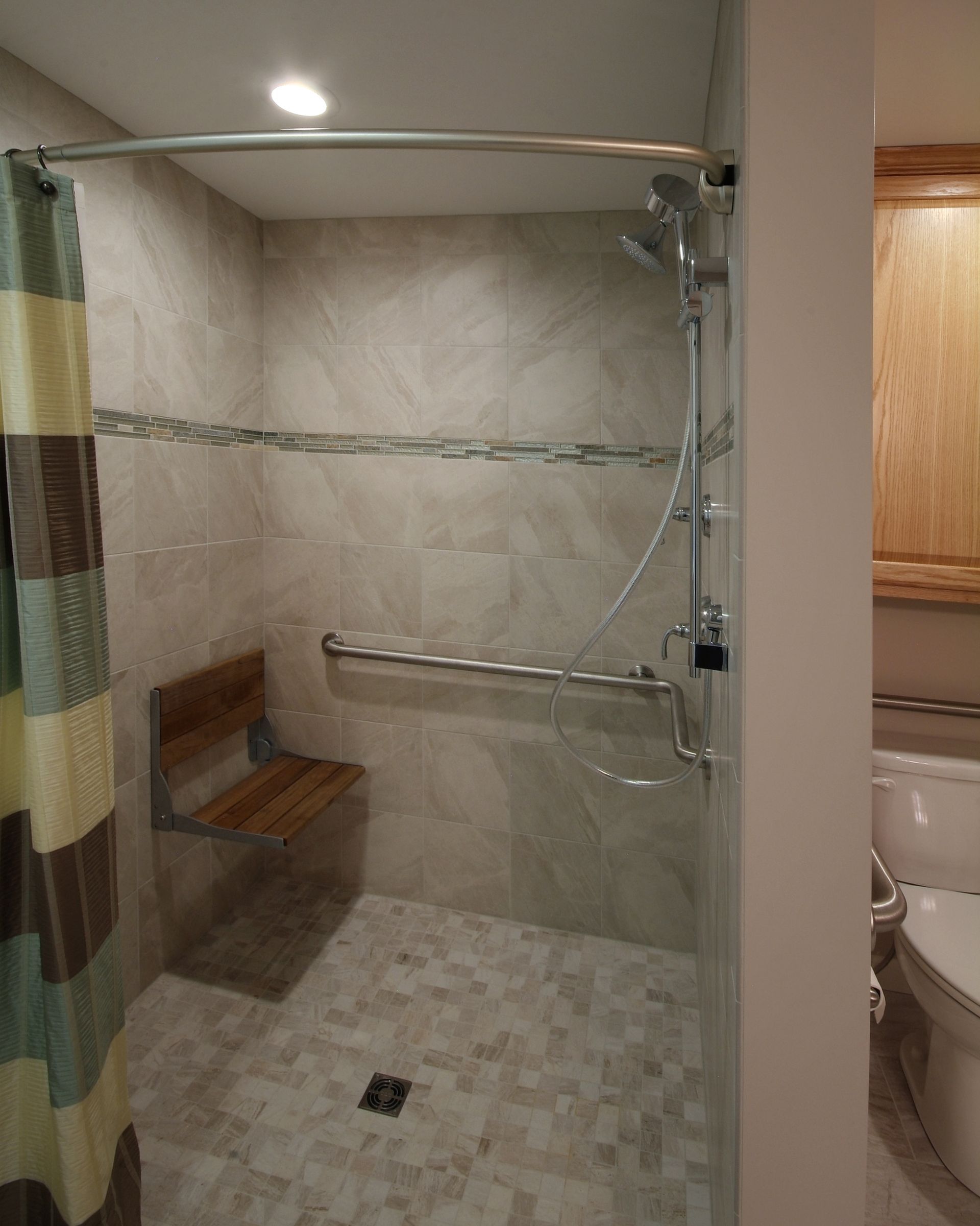 Accessible bathroom shower with bench, grab bars, and tiled walls