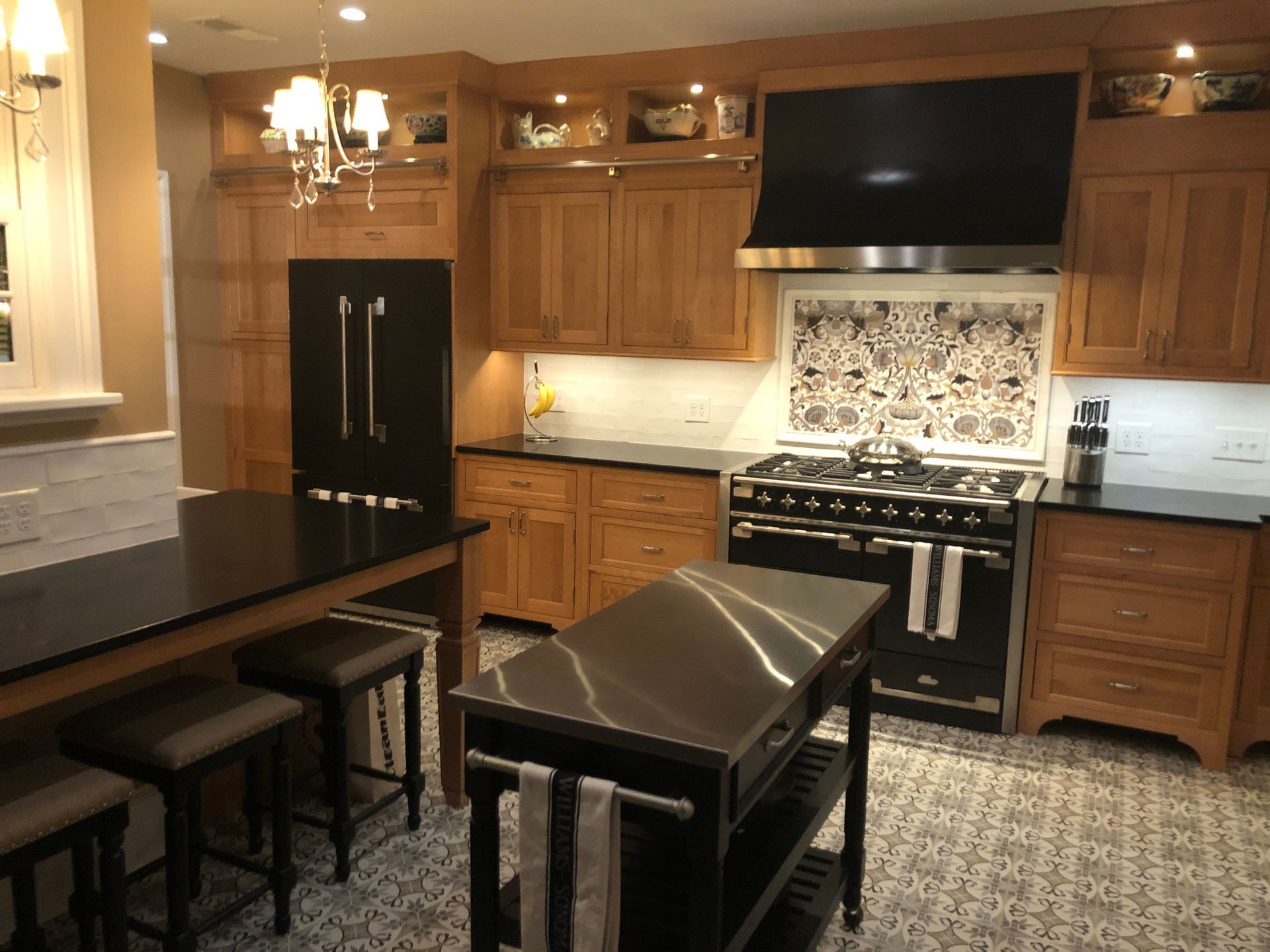 Modern kitchen with wood cabinets, black appliances, island, and patterned rug