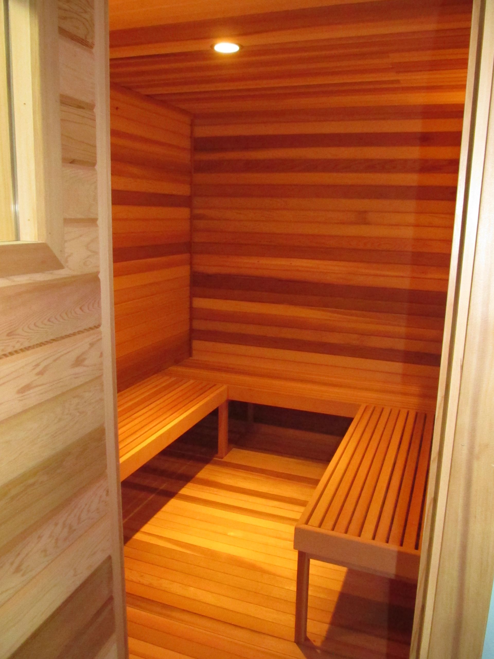 Small wooden sauna with warm lighting and bench seating
