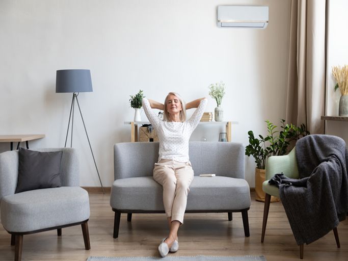 Relaxed older woman sitting on couch in air conditioner room