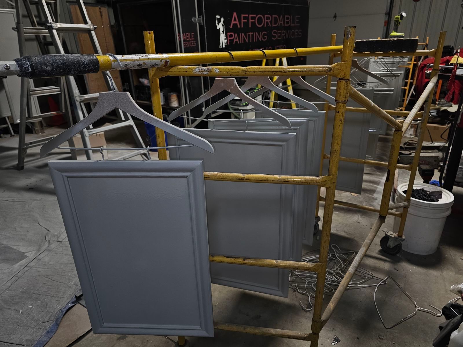 a bunch of cabinet doors are hanging on a rack in a room .